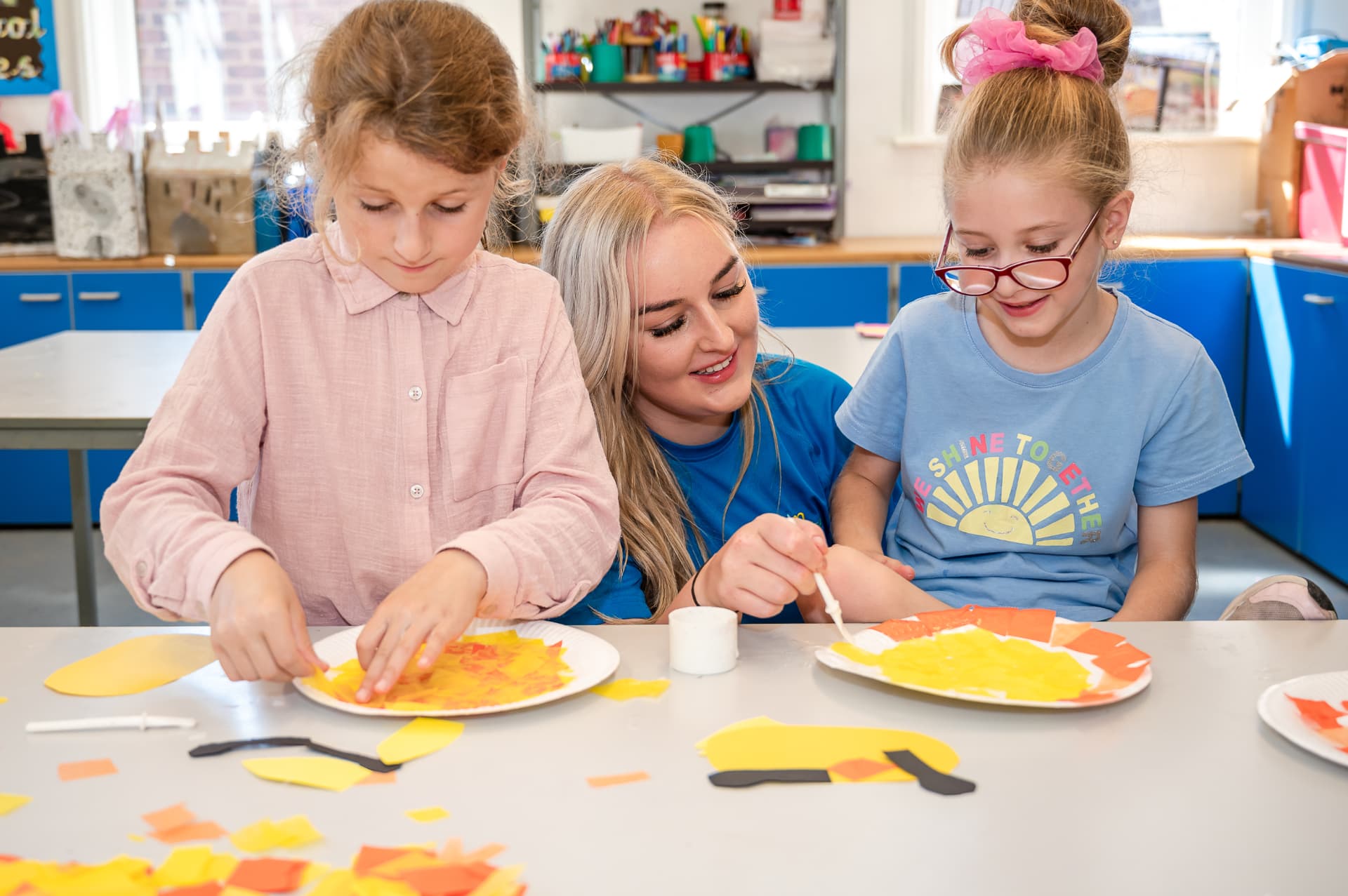 Girls making paper plate crafts with a coach