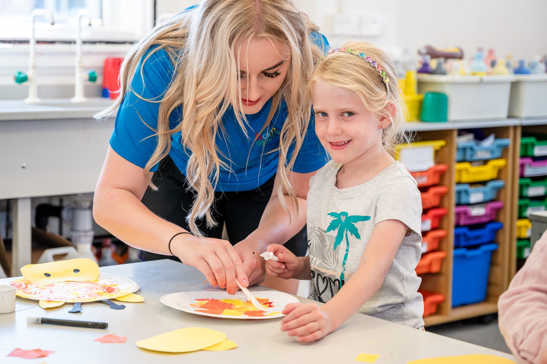 Coach helping a girl with a paper plate craft