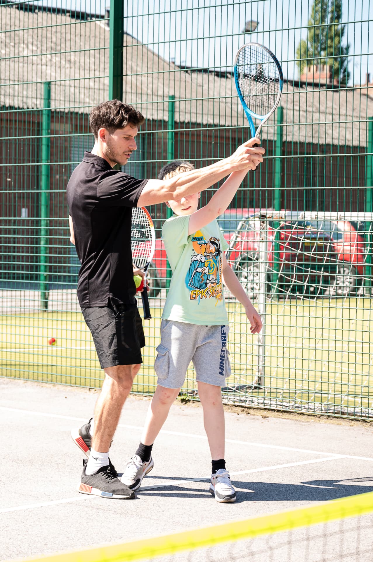 Coach helping a boy with his tennis swing