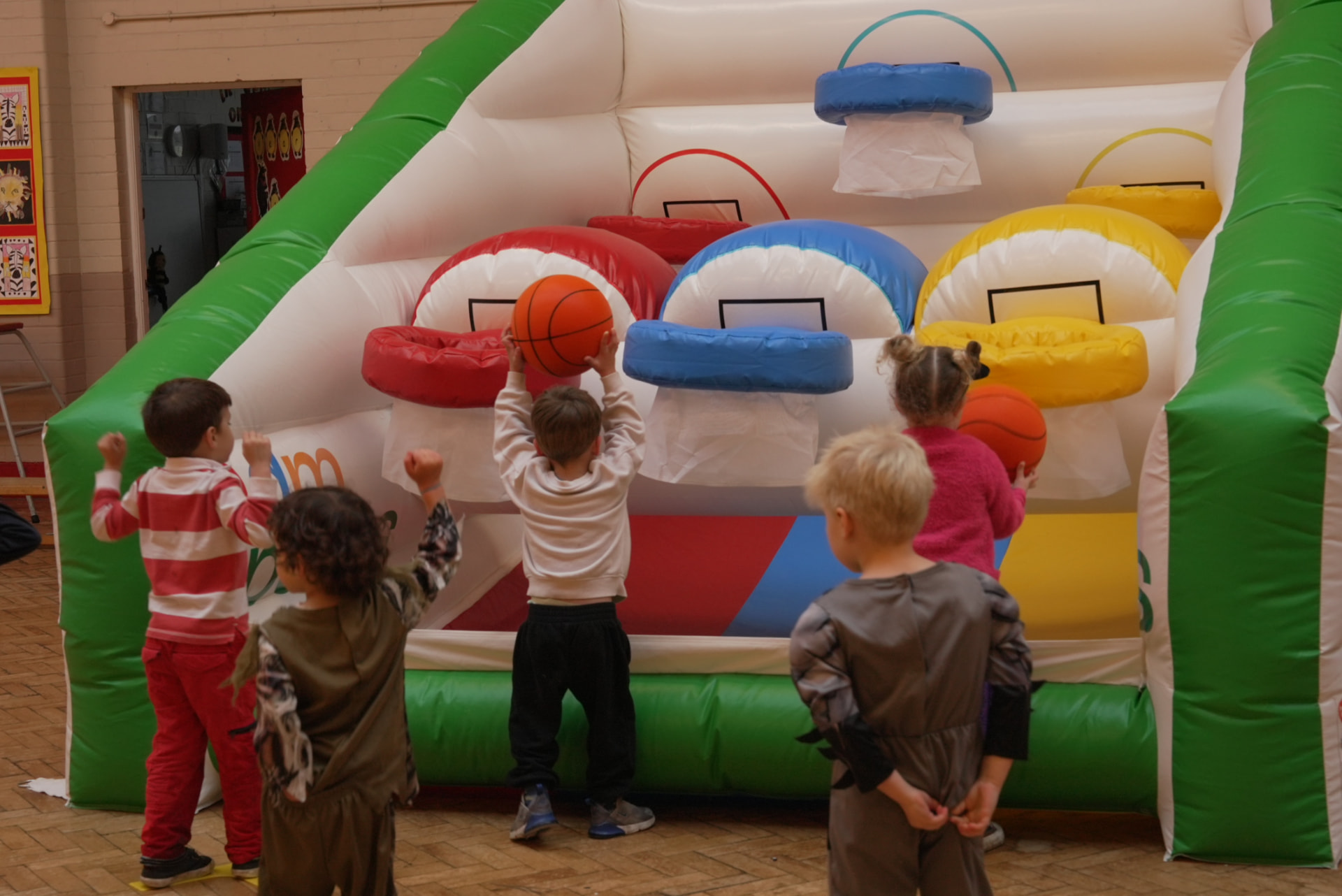 Young children playing the inflatable basketball game at a school event