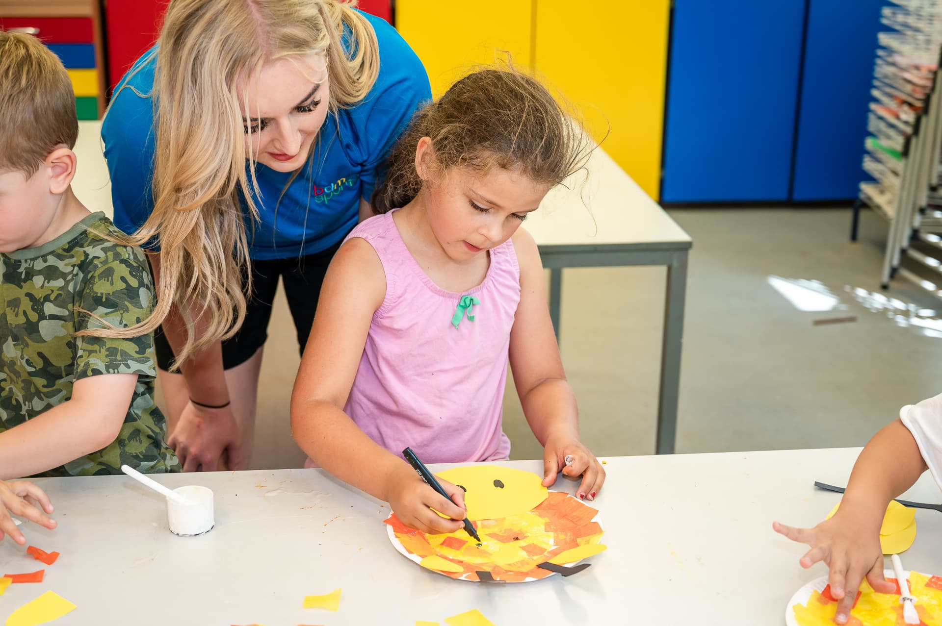 Child drawing on her craft with a coach watching